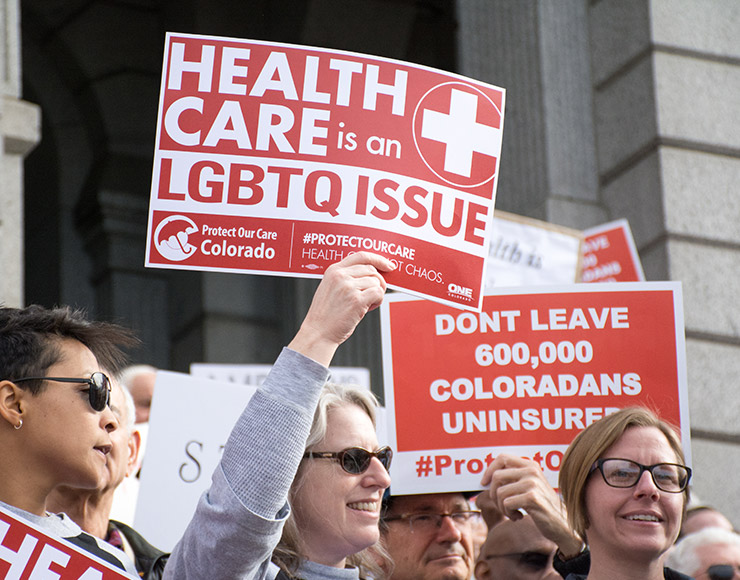 Person holding up a sign that says Health Care is an LGBTQ issue