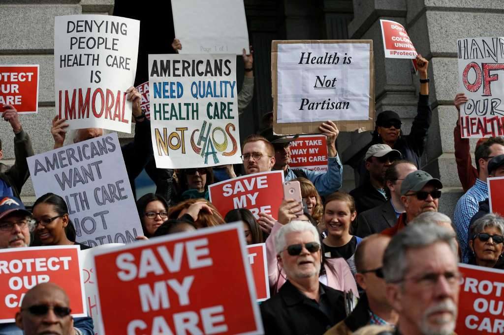 Large group of Coloradans outside the Colorado Capitol holding signs about necessity of health care. For example a sign saying Save My Care.
